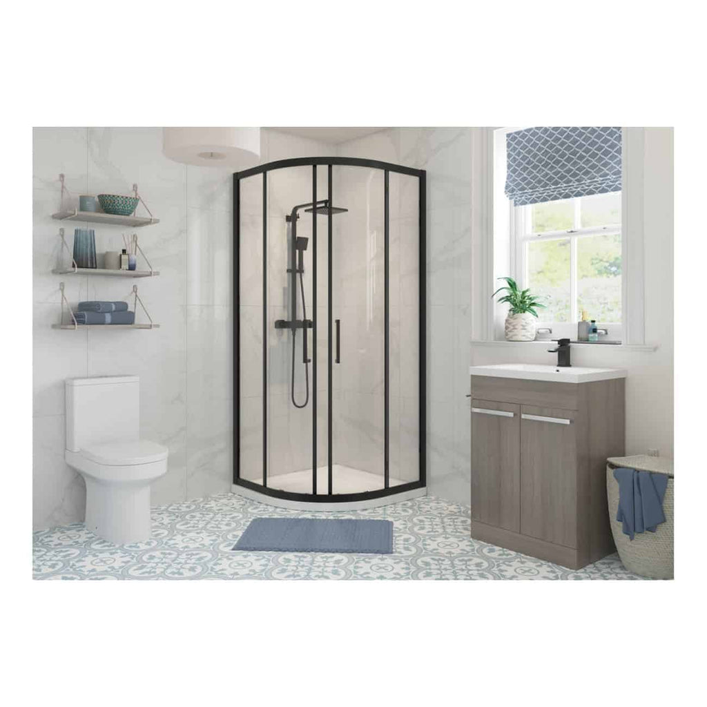 Modern bathroom with a black-framed corner shower enclosure, white marble walls, grey vanity cabinet with white countertop, patterned floor tiles, and a large window with blue roman shade.