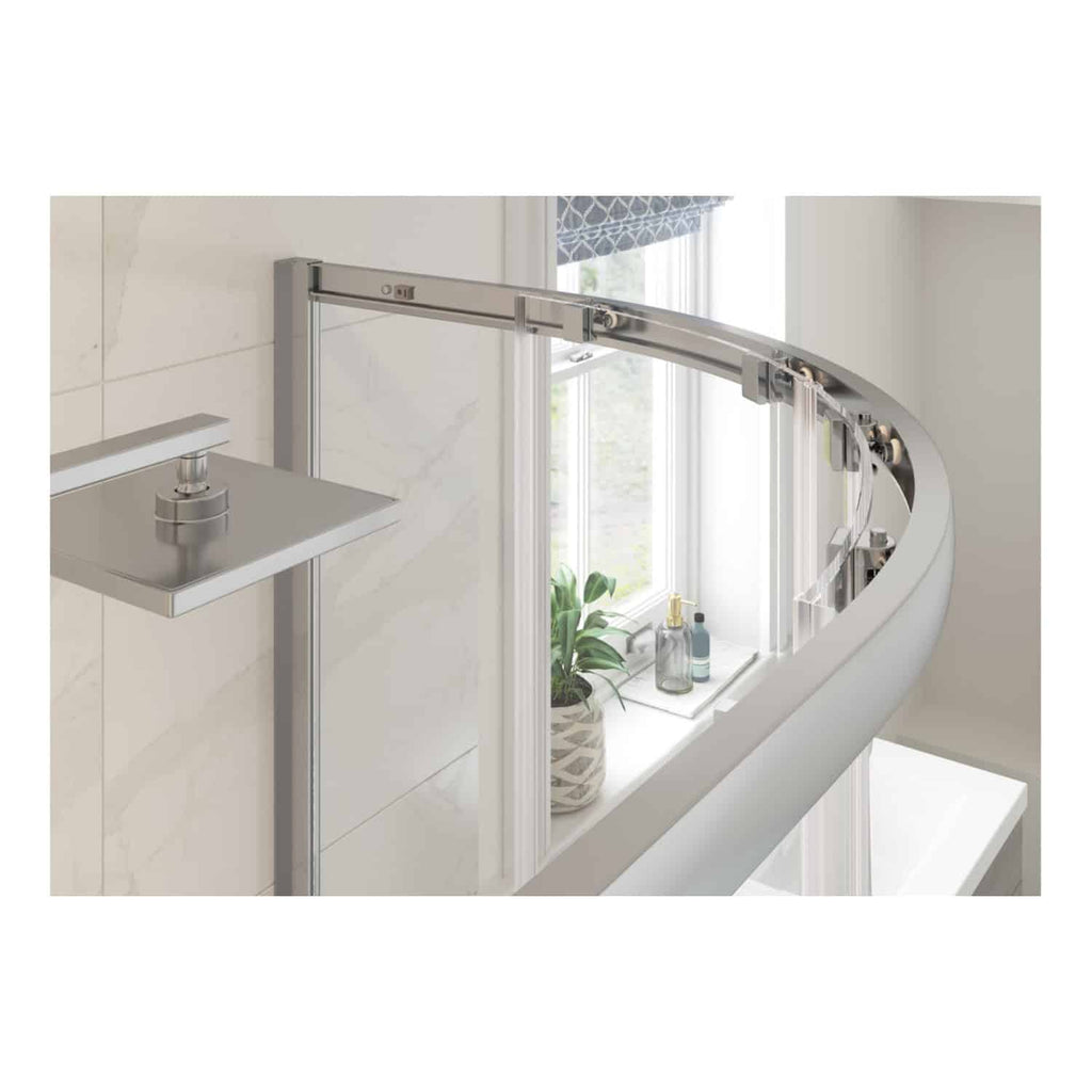 AlT text: Modern curved glass shower door installed in a contemporary bathroom with white tiled walls and natural light from a window with decorative curtains.