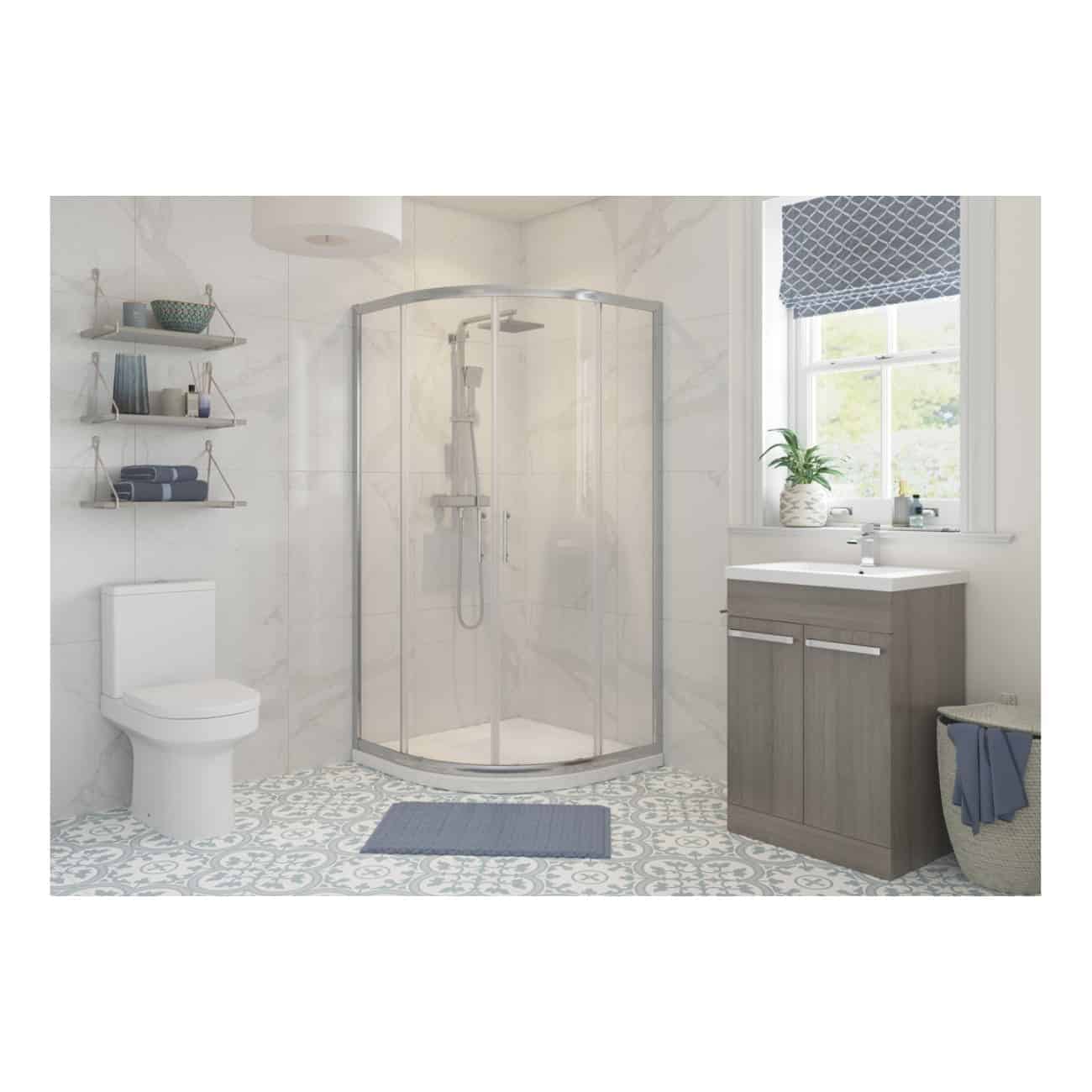 Modern shower bathroom with a curved glass shower enclosure, white and grey tiled walls, a wooden vanity with a sink, a toilet, and decorative shelving with towels and accessories for stylish bathroom decor.