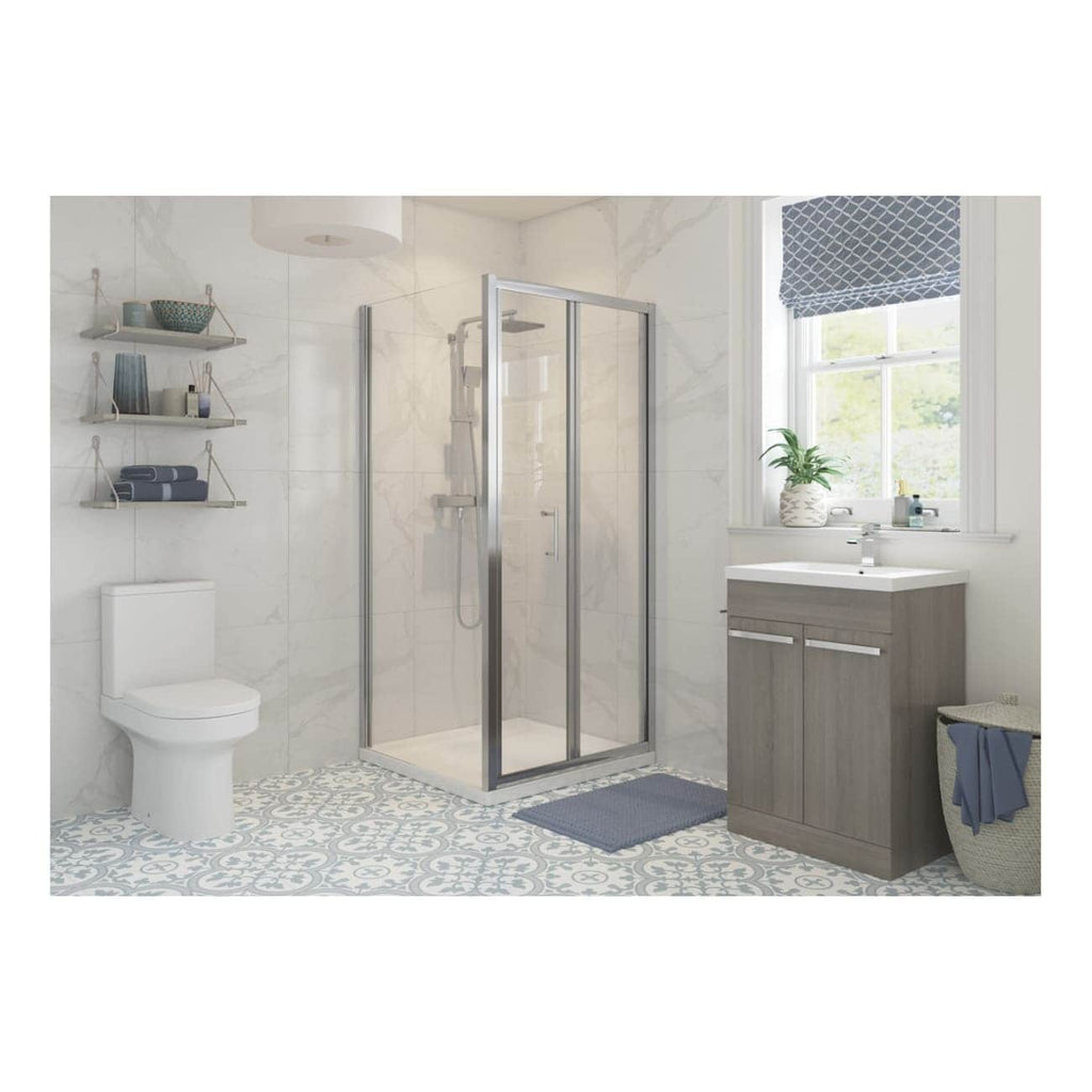 Contemporary bathroom with walk-in shower, white toilet, vanity with sink, decorative patterned floor tiles, and window with natural light and plant decor, showcasing modern bathroom design.