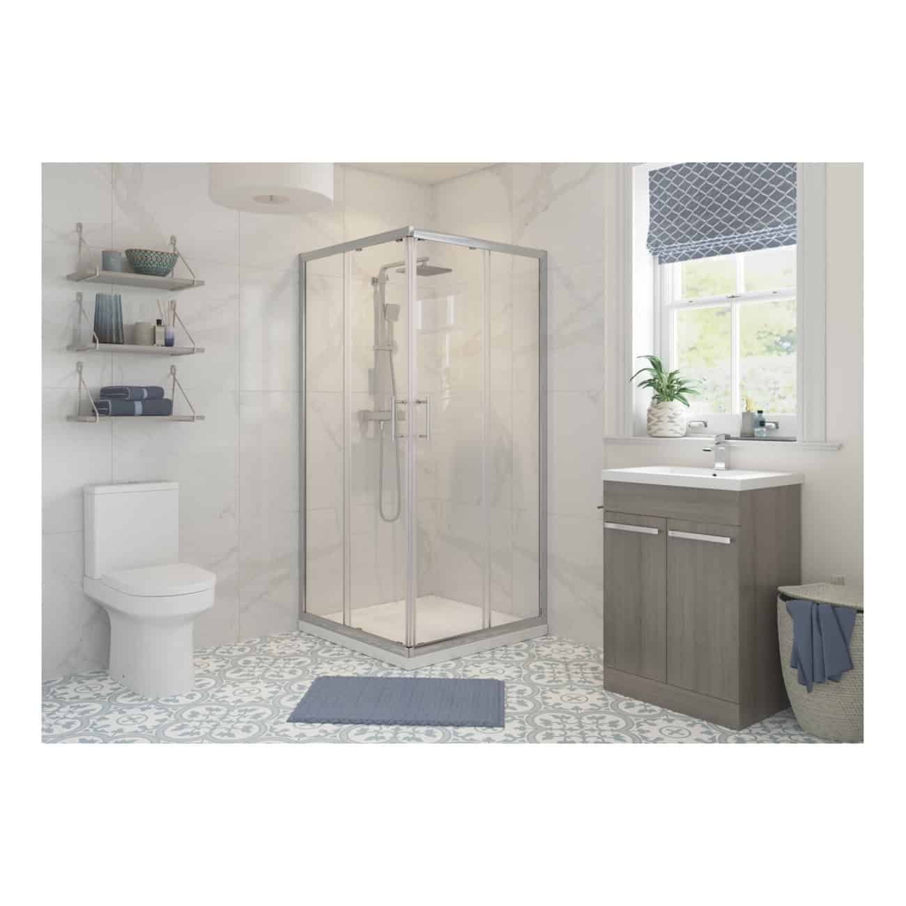 Modern bathroom with walk-in shower, ceramic toilet, grey vanity unit, decorative patterned floor tiles, and natural light from a large window with a blue Roman blind.