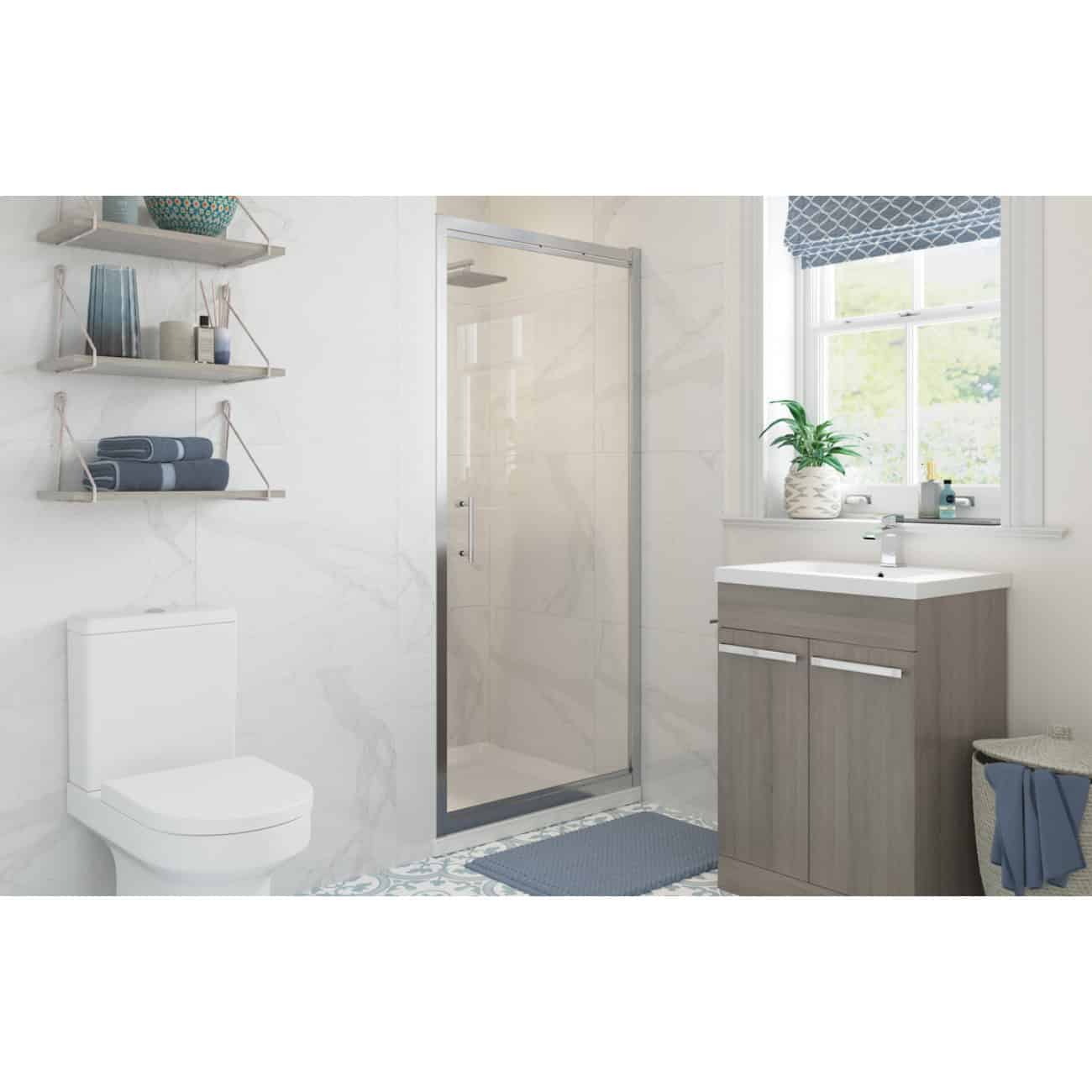 Modern bathroom with walk-in shower, white toilet, grey vanity unit, and decorative shelves with towels and accessories, featuring natural light from a window and subtle blue accents.