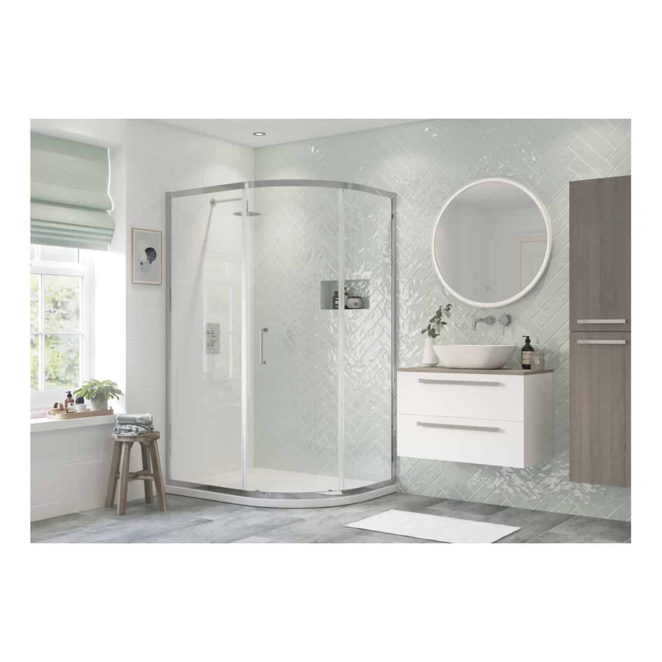 Modern bathroom with corner shower enclosure, white vanity with vessel sink, illuminated round mirror, grey wooden cabinets, and natural light from a window, creating a sleek and contemporary space.