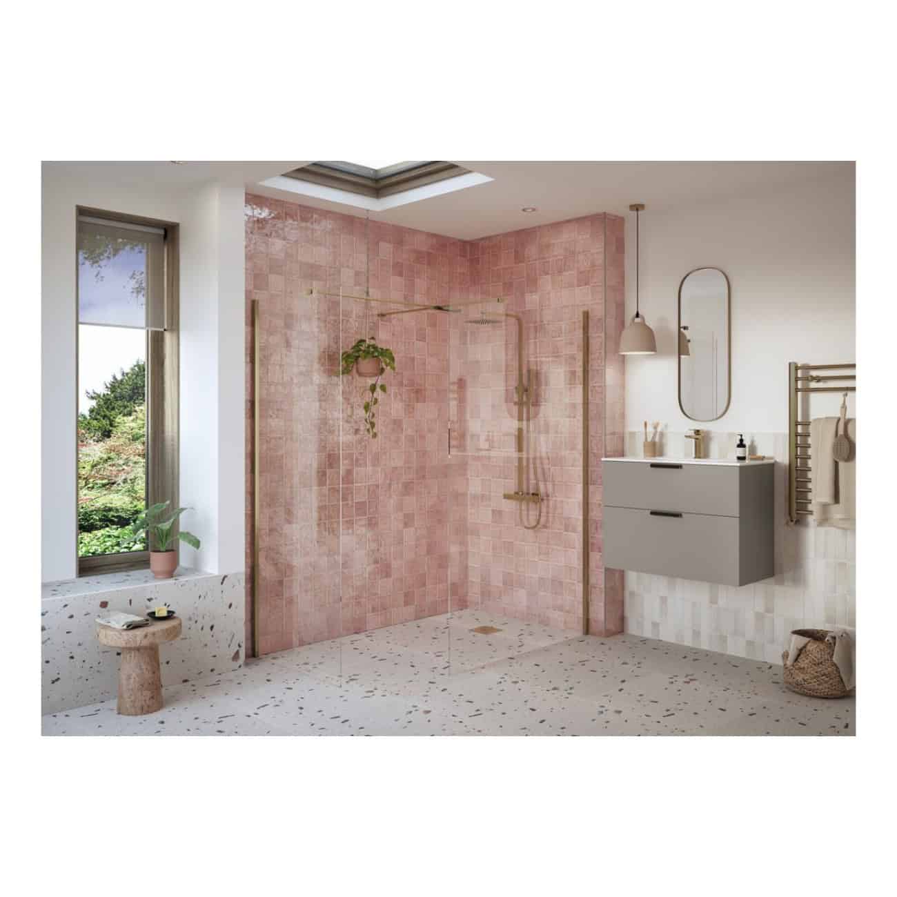 Vibrant pink tiled walk-in shower with modern brass fixtures in a contemporary bathroom featuring terrazzo flooring and minimalist vanity and mirror.