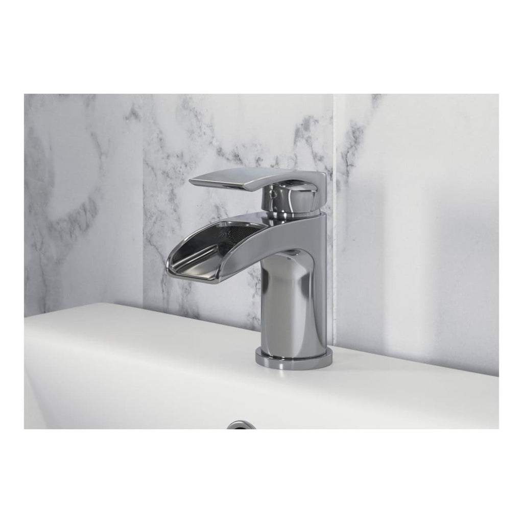 Shiny chrome bathroom tap with a modern design, mounted on a white ceramic sink with a marble tiled wall behind it. Perfect for stylish and functional bathroom upgrades.