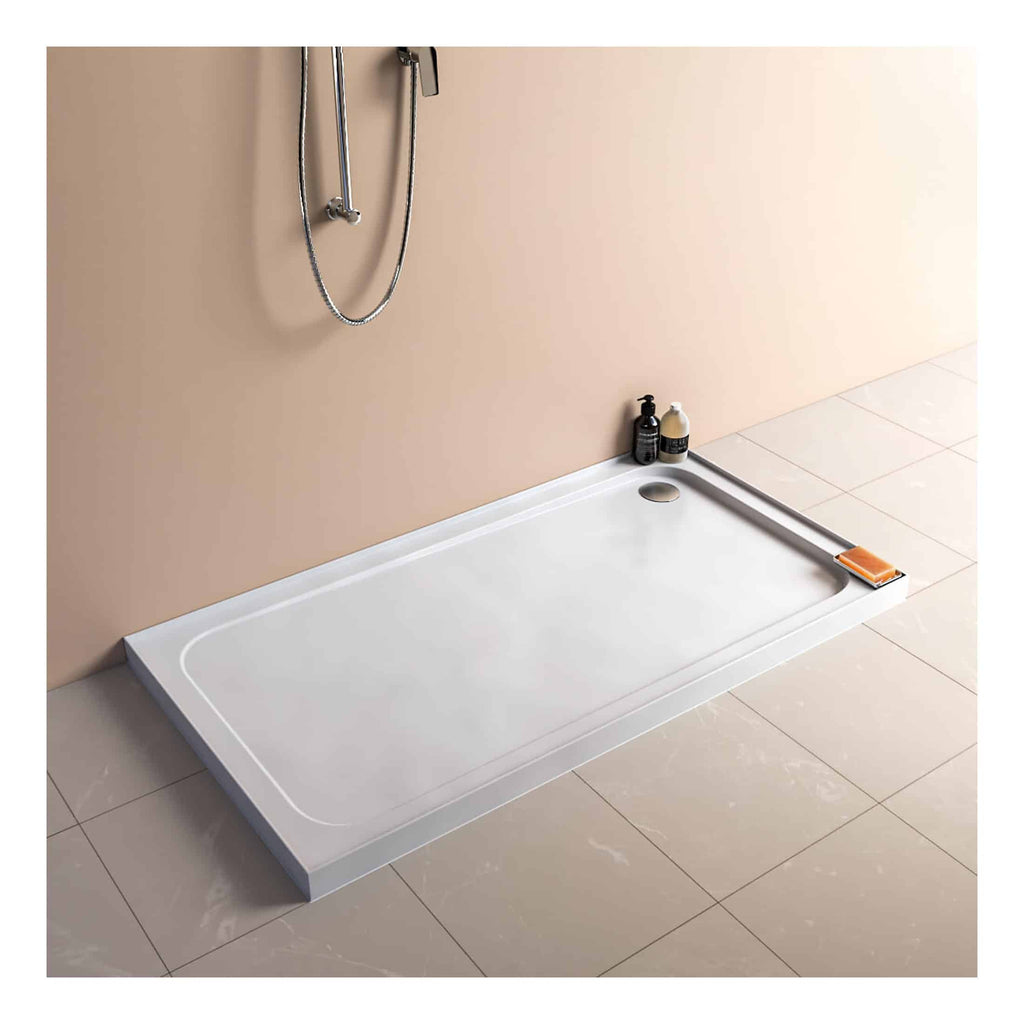 Sleek white shower tray with modern minimalist design, situated on beige tiled floor against a soft pink wall, with two bottles of shower essentials nearby.
