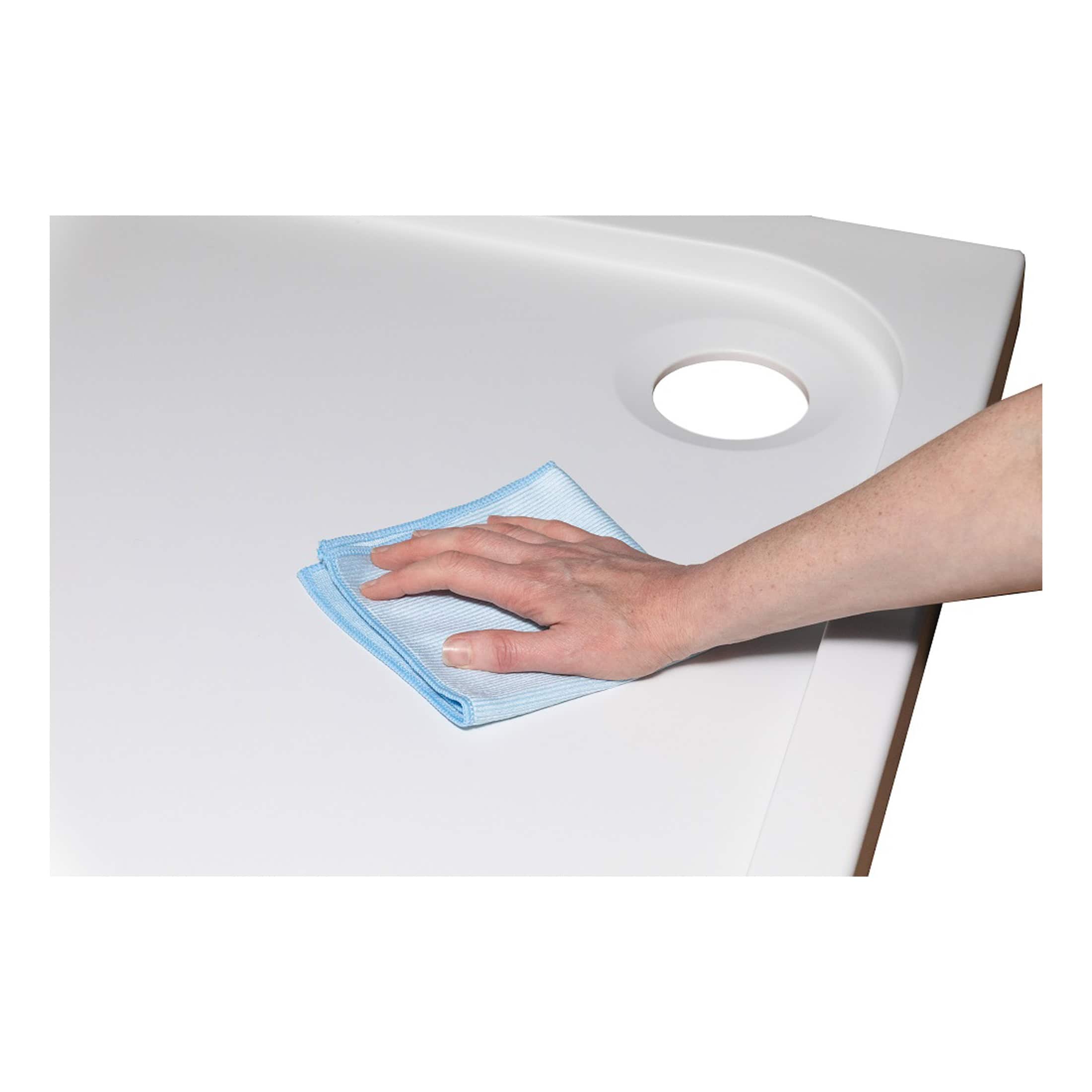 Microfiber cloth being used to clean a white bathroom sink for hygiene and maintenance purposes.