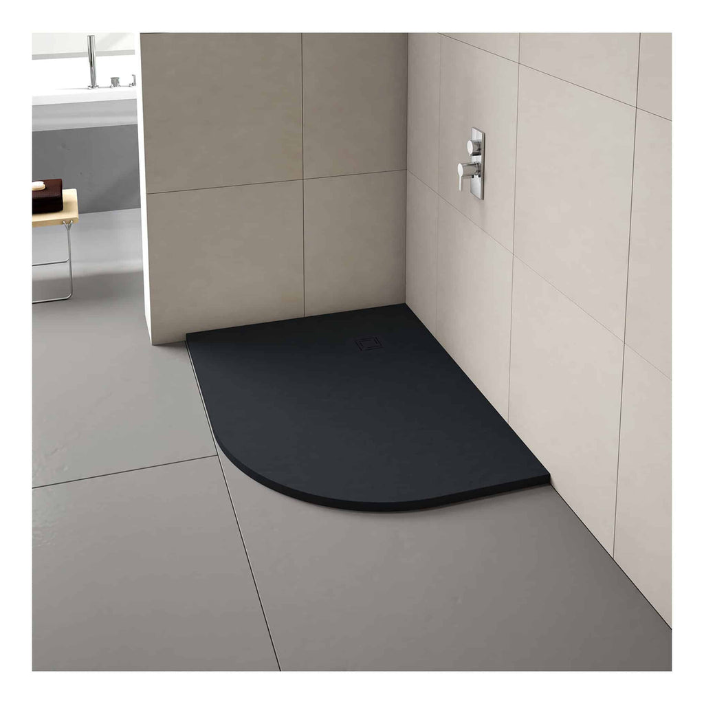 Silicone black shower tray with a curved front edge, installed on a grey tiled bathroom floor with a wall-mounted shower control. Modern and minimalist bathroom design featuring durable waterproof surfaces.