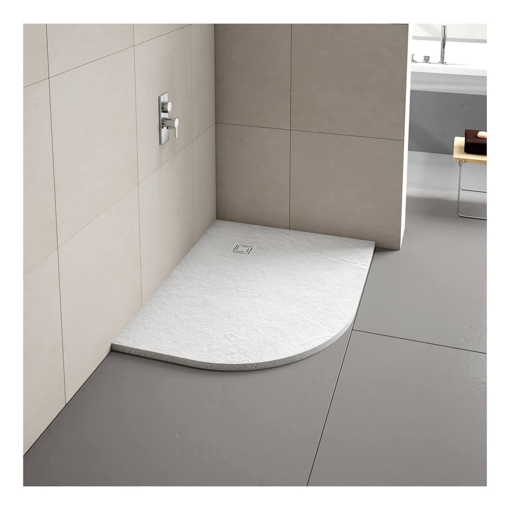 Light grey textured shower tray with rounded front edge and square drain, installed in a modern beige tiled bathroom with wall-mounted controls and minimalist design.