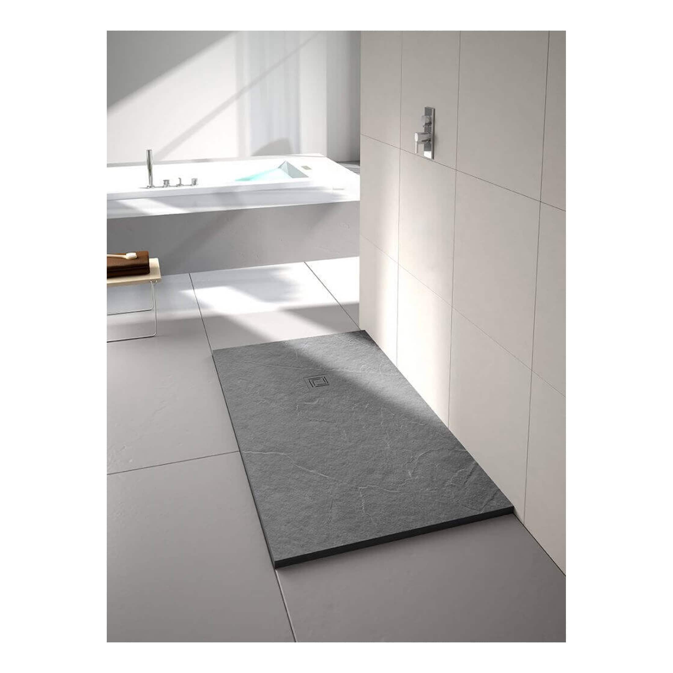Slate shower tray in a modern white bathroom with minimalist design, featuring large tiles, sleek fixtures, and natural light for a contemporary and elegant look.