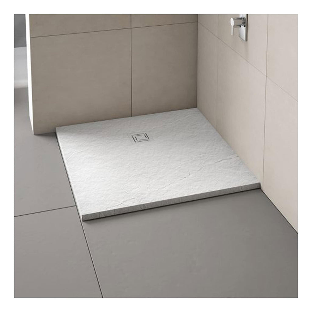 Modern white shower tray with textured surface and centred drain in minimalist bathroom setting.