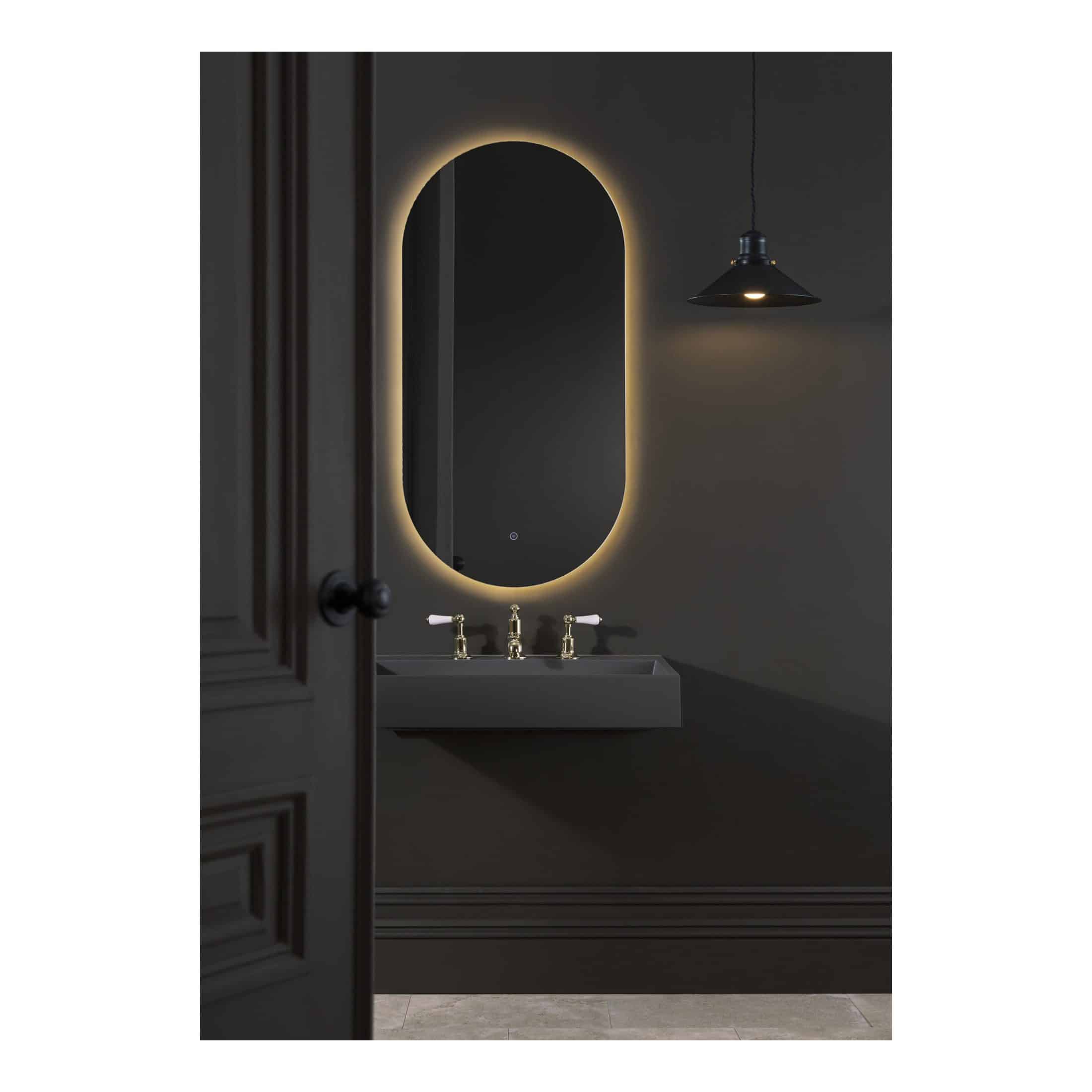 Elegant oval backlit mirror in a modern bathroom with dark wall, gold fixtures, and ambient lighting, perfect for contemporary bathroom design and creating a luxurious atmosphere.