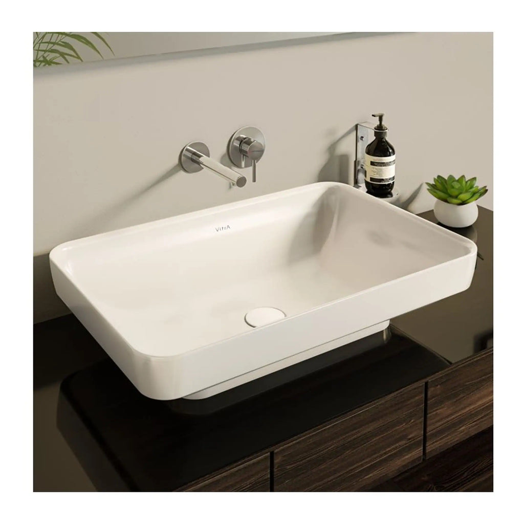 Sleek rectangular white bathroom sink with modern wall-mounted tap and minimalist design, set on a dark wood vanity with décor accessories.