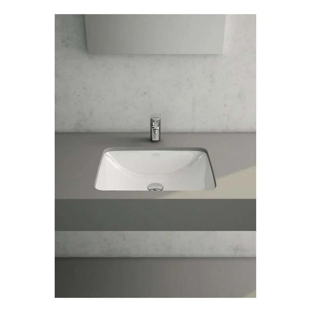 Contemporary white bathroom sink with a sleek chrome tap set against a minimalist grey vanity unit and textured wall background.