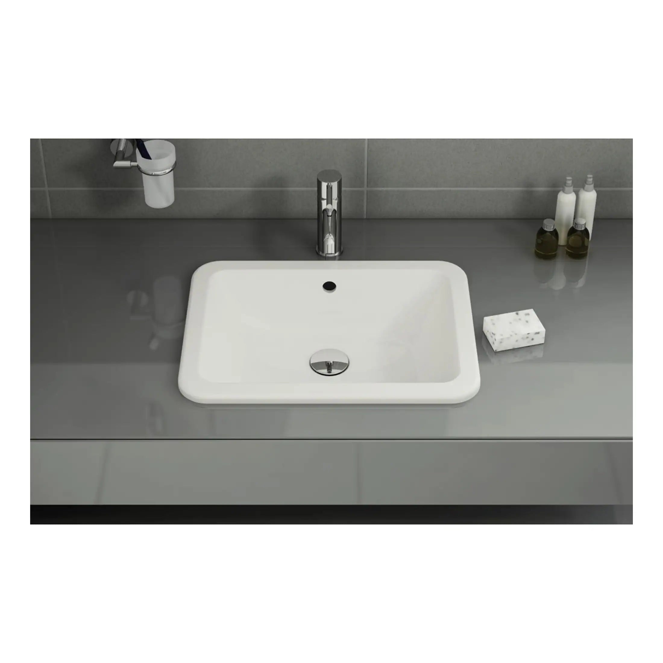 Sleek white bathroom sink with modern chrome tap on a grey countertop, accompanied by toiletries and accessories, ideal for contemporary bathroom design.