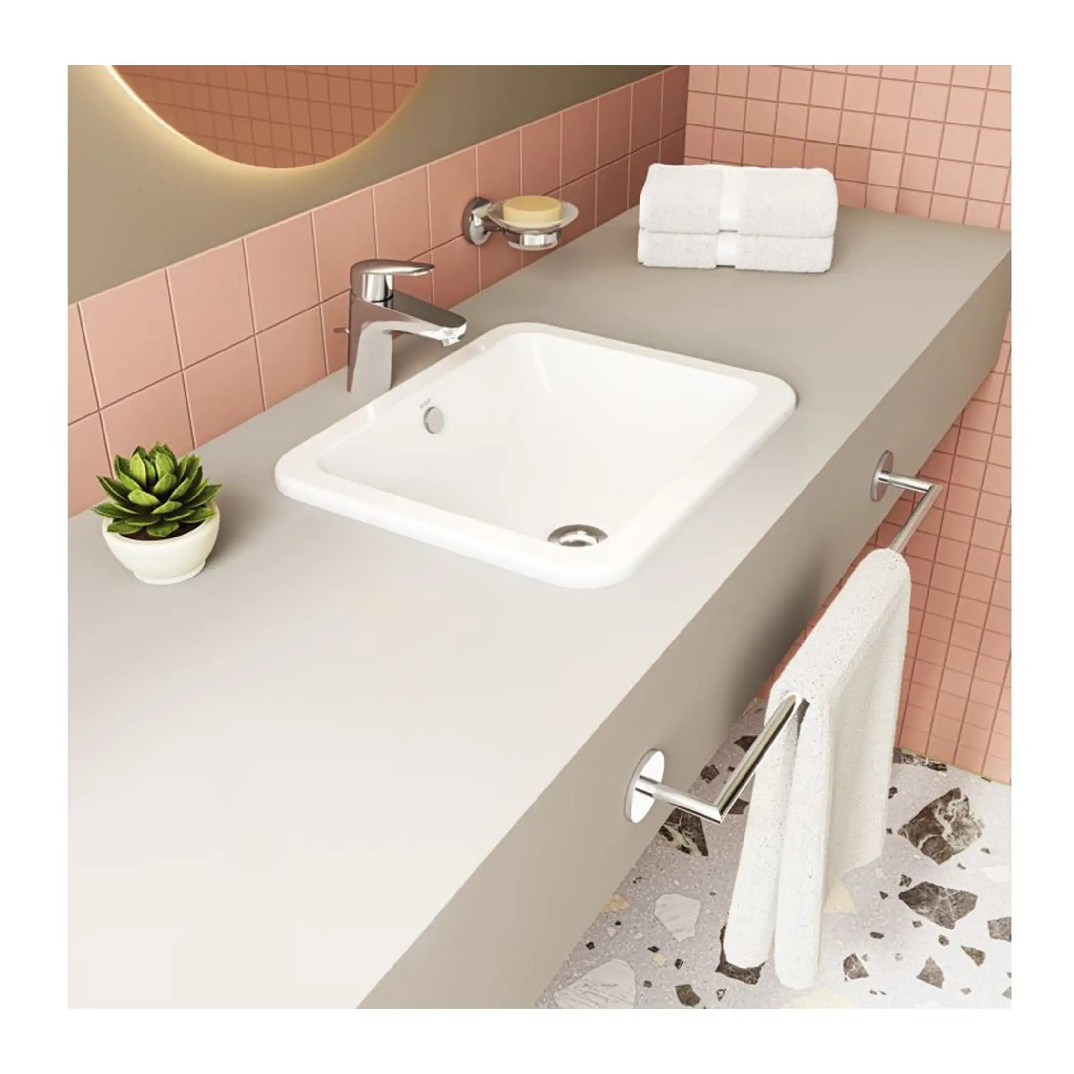 Modern bathroom sink with sleek chrome faucet, surrounded by neatly folded towels, a small potted plant, and everyday toiletries, set against a pink tiled wall for a contemporary bathroom design.