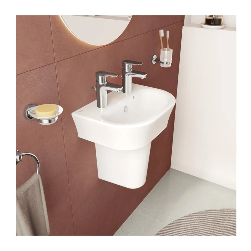 Sleek white wall-mounted bathroom sink with dual chrome taps, set against a modern terracotta tiled wall with accessories including soap dish, toothbrush holder, and towel ring for contemporary bathroom design.