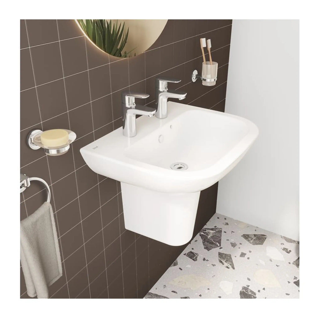 Smooth white bathroom sink with dual chrome faucets, mounted on a modern wall with dark tile background and contemporary decor accents.