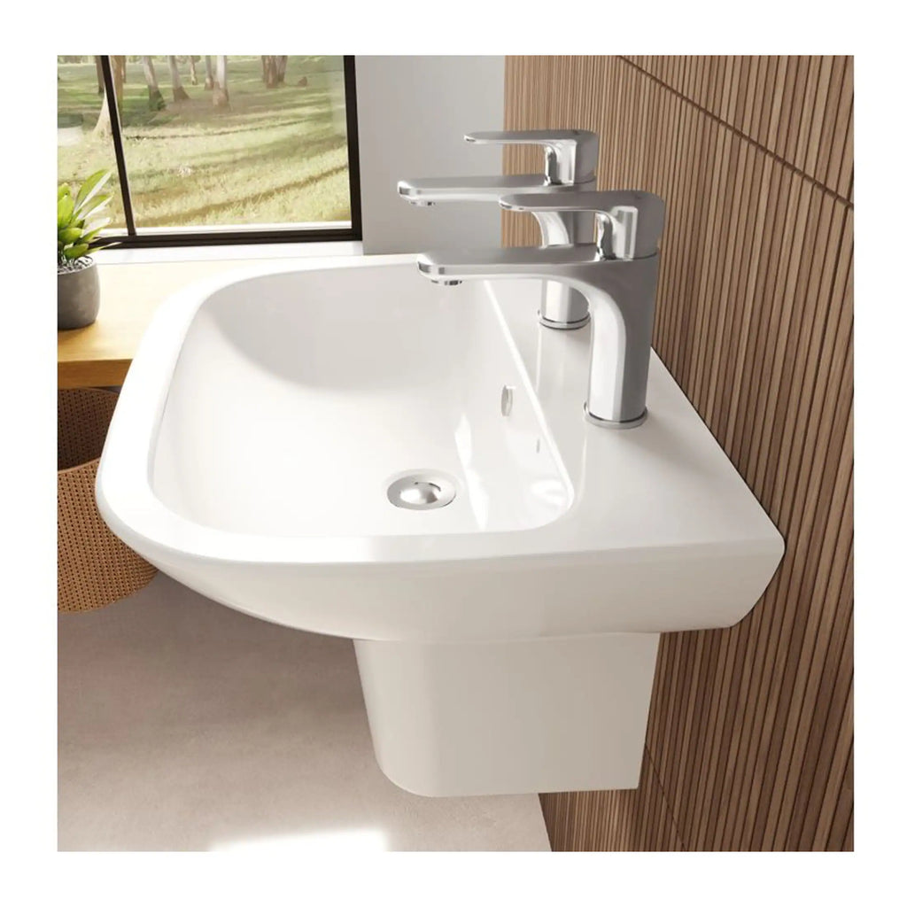Sleek modern white bathroom sink with dual faucets and chrome fittings, set against a wooden wall with a window view of greenery, ideal for contemporary bathroom designs.