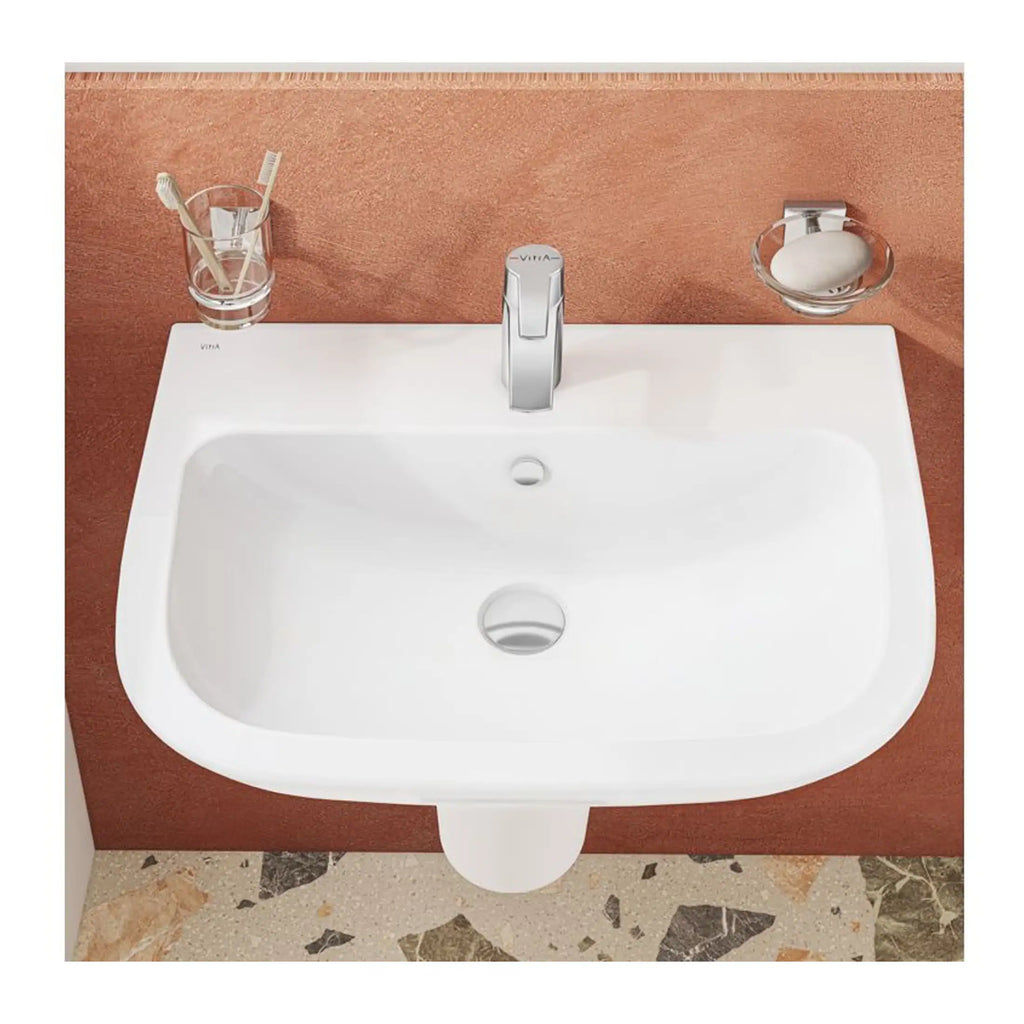 Modern white bathroom sink with chrome faucet, mounted on a textured terracotta wall with matching accessories for stylish bathroom decor.