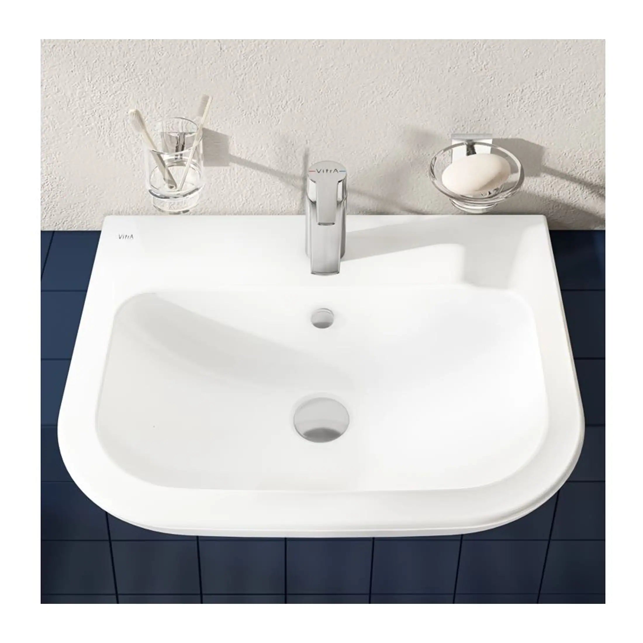 Sleek white bathroom sink with modern chrome tap, set against a textured off-white wall with blue tiled countertop, perfect for contemporary bathroom design.