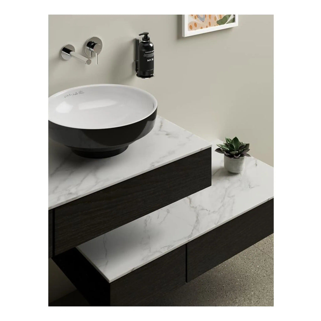 Sleek black and white ceramic bathroom basin on a modern vanity unit with marble top, wall-mounted chrome faucet, black soap dispenser, and a small potted plant, stylish bathroom design.
