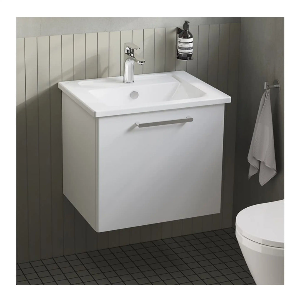 Contemporary white bathroom vanity with integrated sink and chrome handle, wall-mounted for space-saving, in a modern bathroom setting with wall tiles and accessories.