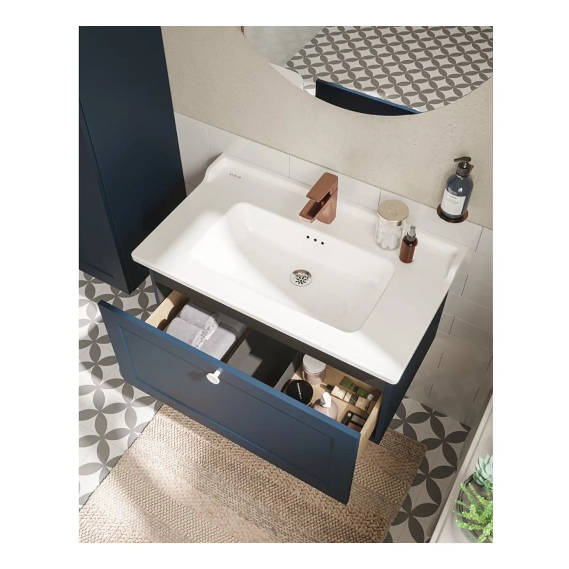 Sleek modern bathroom vanity with a white sink, navy blue cabinet, and stylish rose gold faucet, complemented by decorative bathroom accessories and patterned floor tiles.