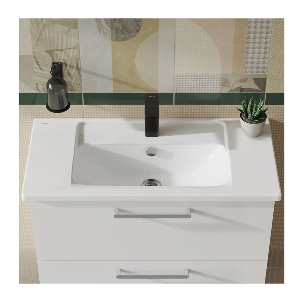 Sleek modern white bathroom sink with integrated storage drawers, black tap, black soap dispenser, and small potted plant on beige tiled bathroom wall.