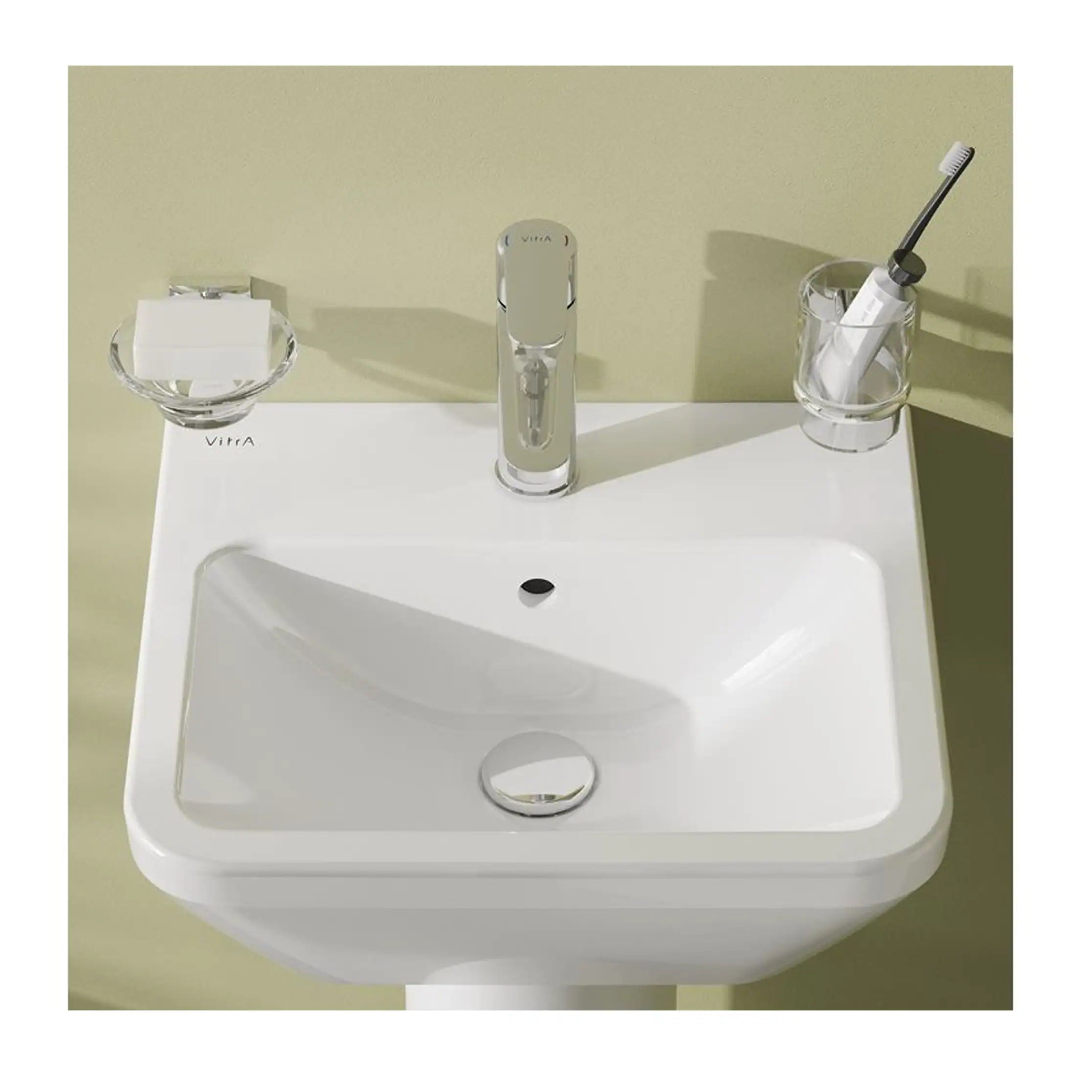 Sleek white bathroom sink with modern chrome faucet, organic soap dish, and a toothbrush holder, ideal for contemporary bathroom design.
