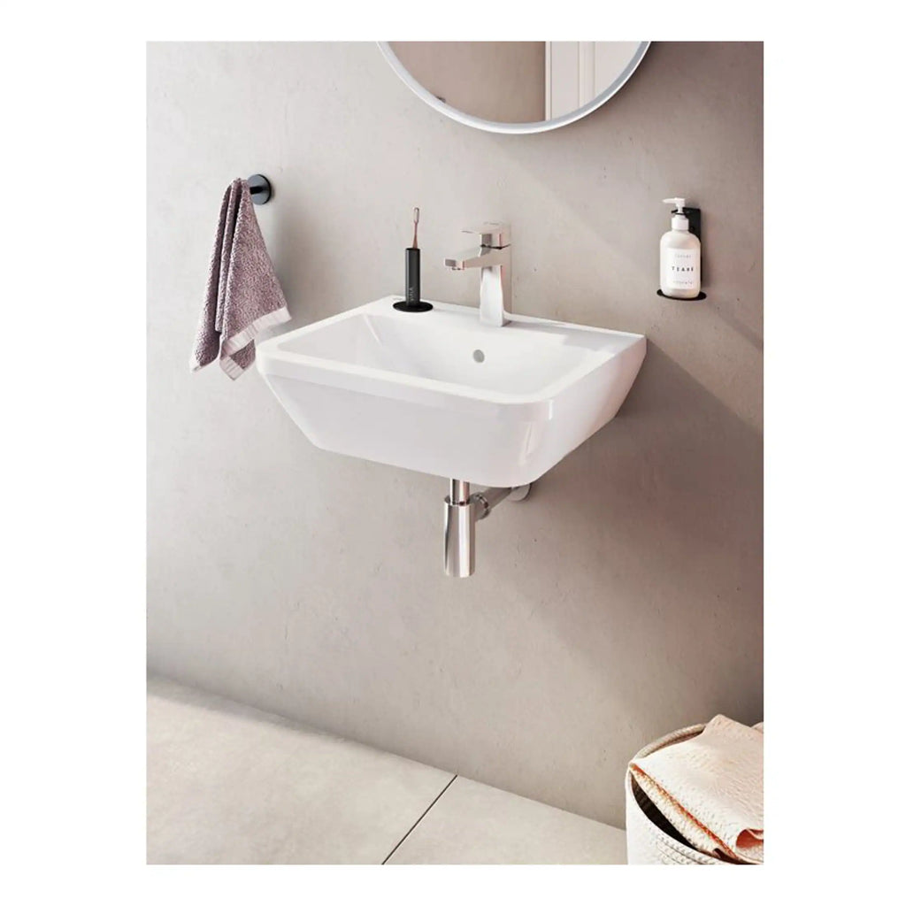 Compact white wall-mounted bathroom sink with chrome faucet and modern accessories, ideal for contemporary bathrooms. Includes towel holder, liquid soap dispenser, and space for essentials, enhancing functional design.