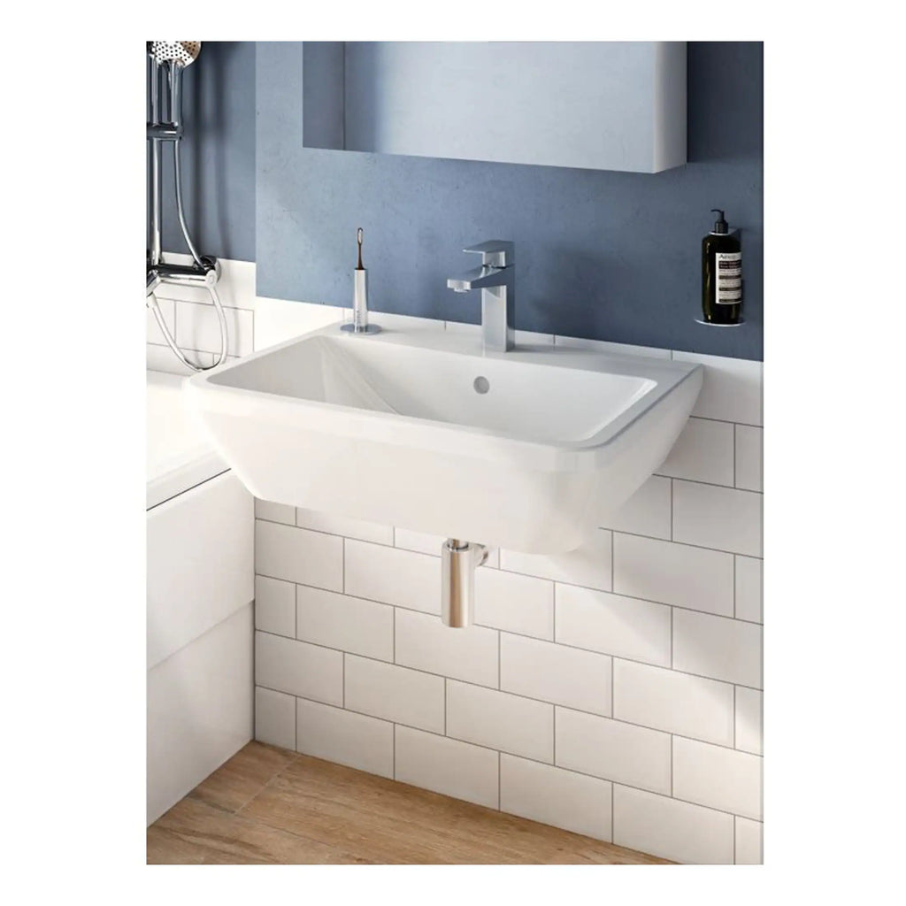 Modern white wall-mounted bathroom sink with a chrome faucet and a minimalist design, set against a stylish blue wall with white tiled lower section. Includes an integrated soap dispenser and reflection in mirror, perfect for contemporary bathrooms.