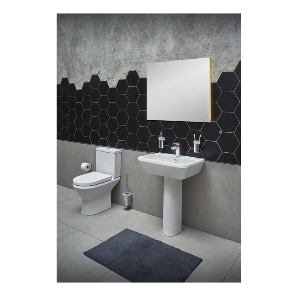 Sleek modern bathroom with black hexagonal tiled wall, white ceramic toilet and pedestal sink, illuminated mirror, and minimalist accessories, showcasing contemporary bathroom design.