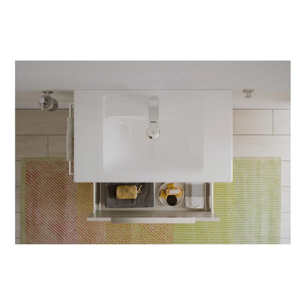 Modern white bathroom vanity with rectangular sink and chrome faucet, surrounded by beige tiled flooring and colourful striped bath mats, showcasing contemporary bathroom design.