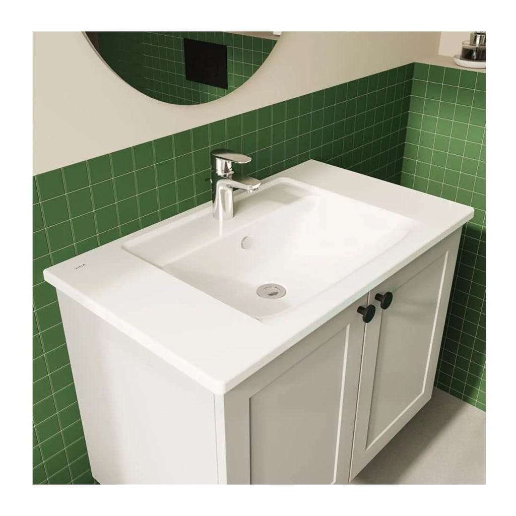 Sleek white bathroom vanity with integrated sink, chrome tap, and black cabinet handles, set against a vibrant green tiled wall for a contemporary bathroom design.