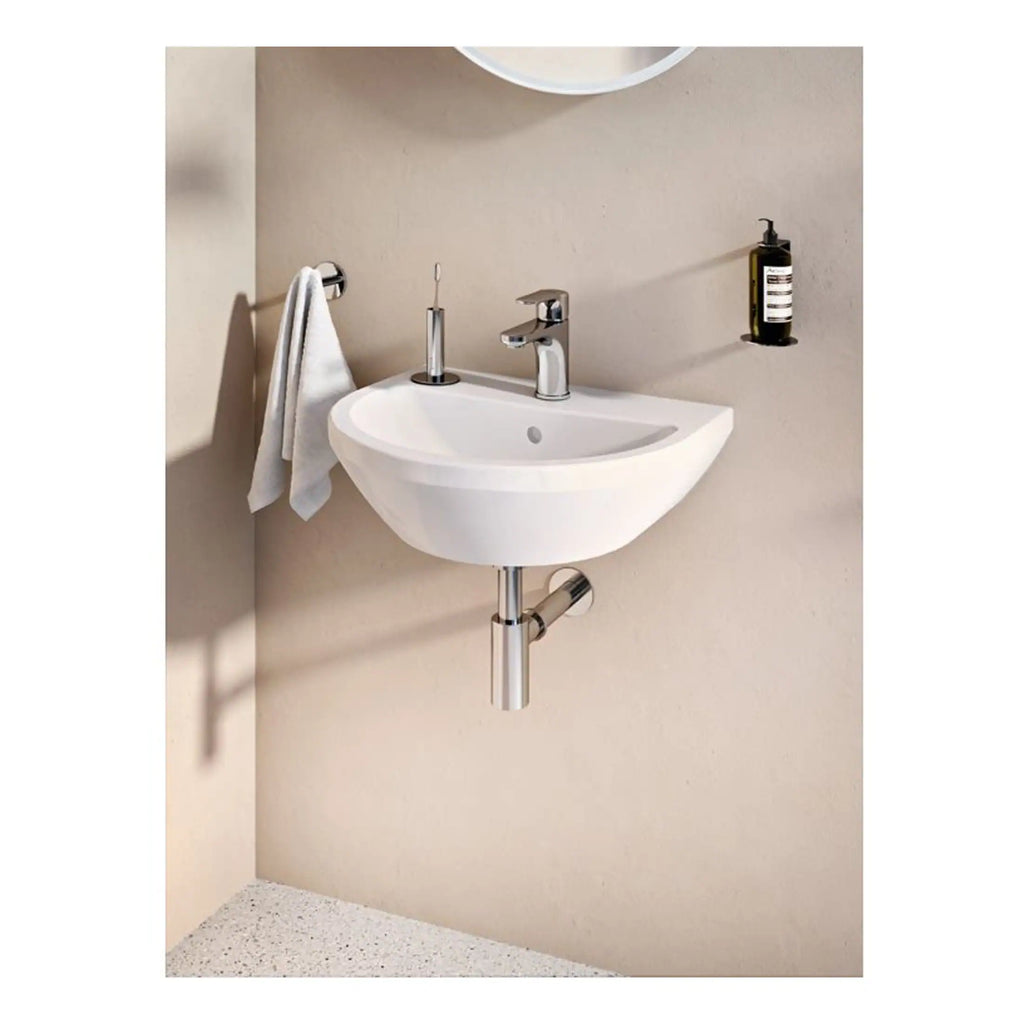 Contemporary wall-mounted white bathroom sink with chrome fixtures, a towel rail, and a soap dispenser for modern bathroom decor.