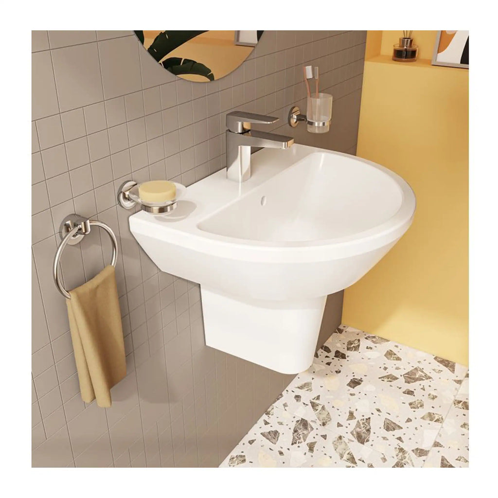 Sleek white wall-mounted bathroom sink with modern chrome fixtures, a beige towel hanging on a circular towel ring, and beige tiled walls with a decorative terrazzo floor.