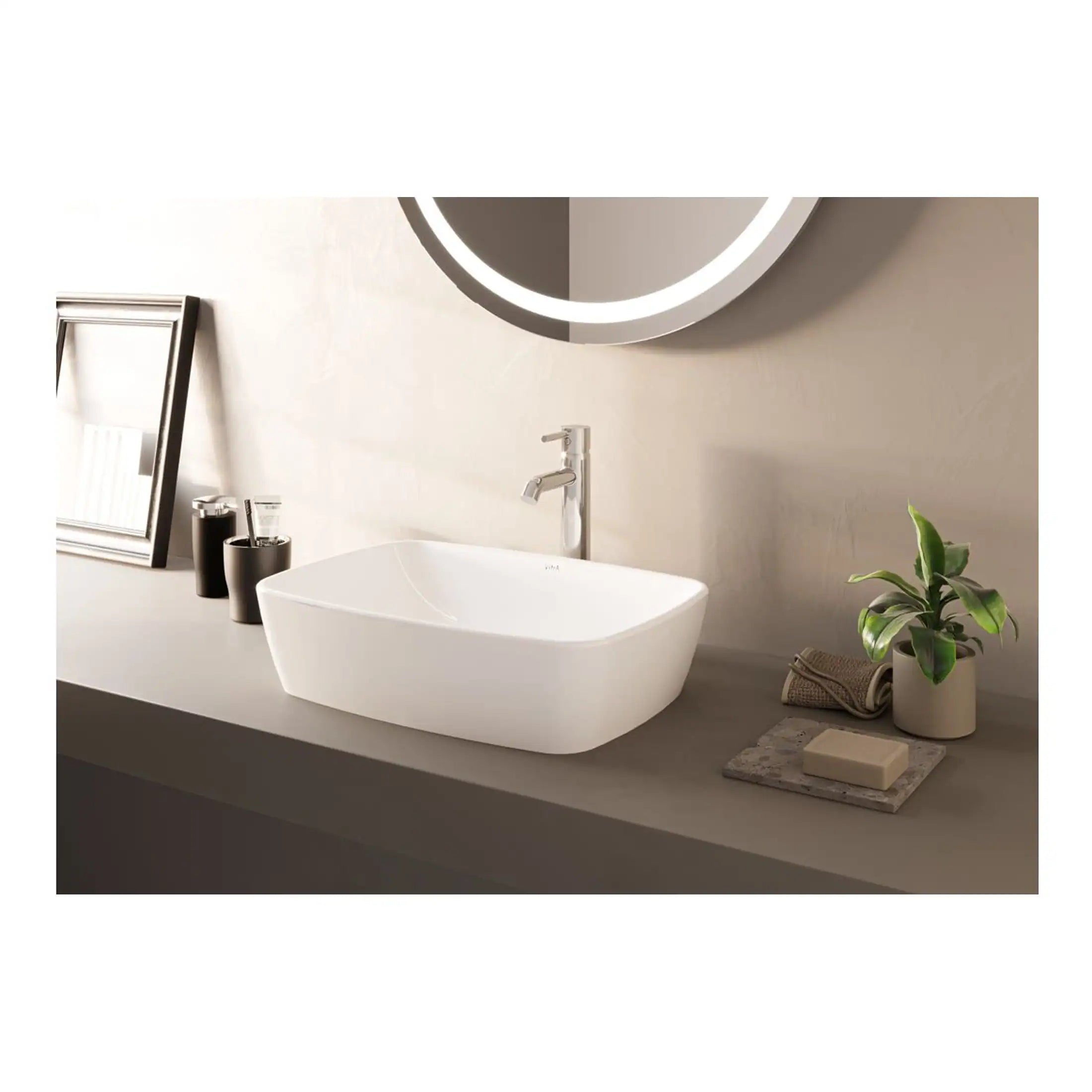 Sleek white bathroom basin with modern minimalist design, mounted on a neutral-toned countertop with contemporary fixtures, complemented by a round illuminated mirror, plant, and stylish accessories for a clean, elegant bathroom look.