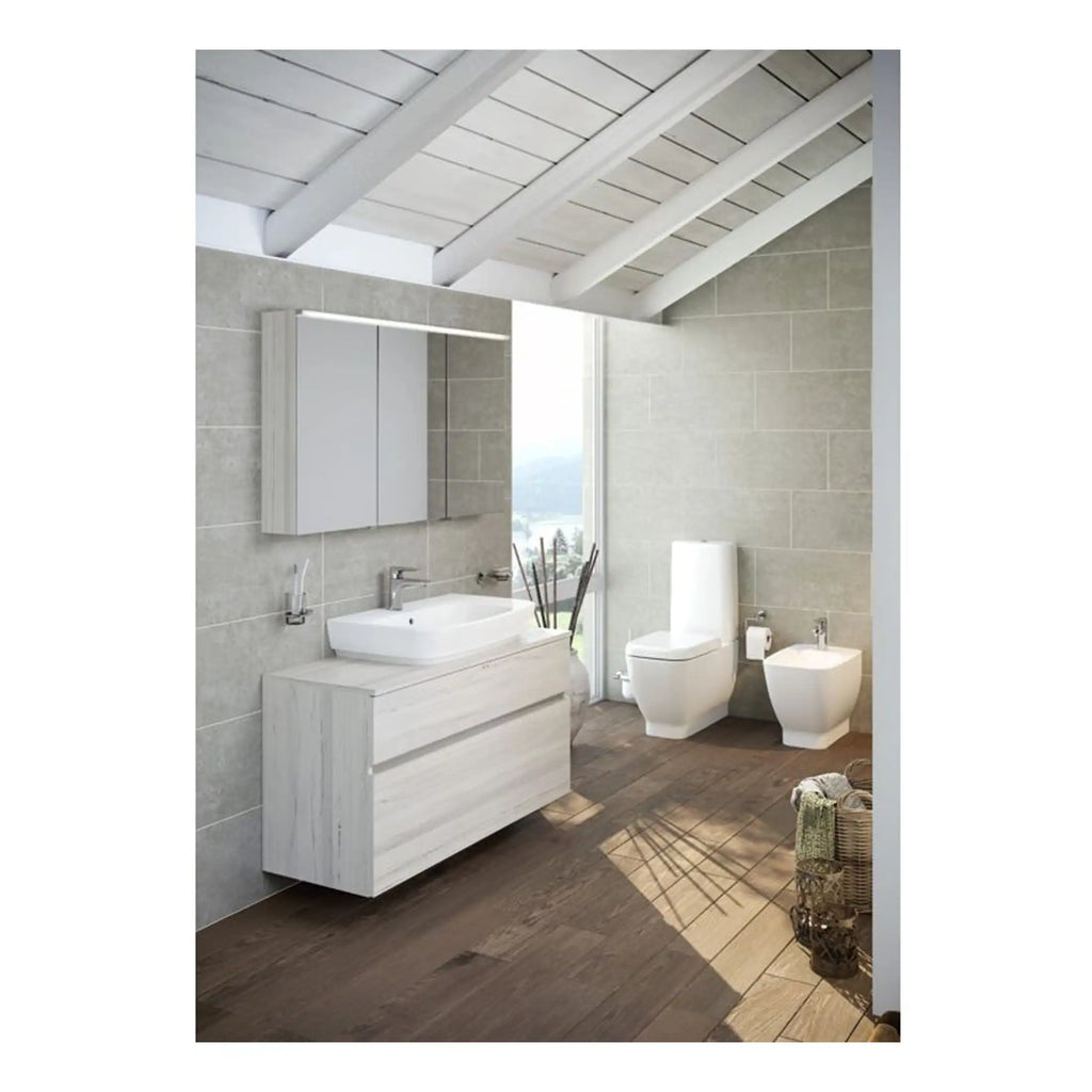 Modern minimalist bathroom with wall-mounted vanity, sleek white sink, large mirror, toilet, bidet, and natural light from a tall window, featuring neutral tones and wooden flooring.