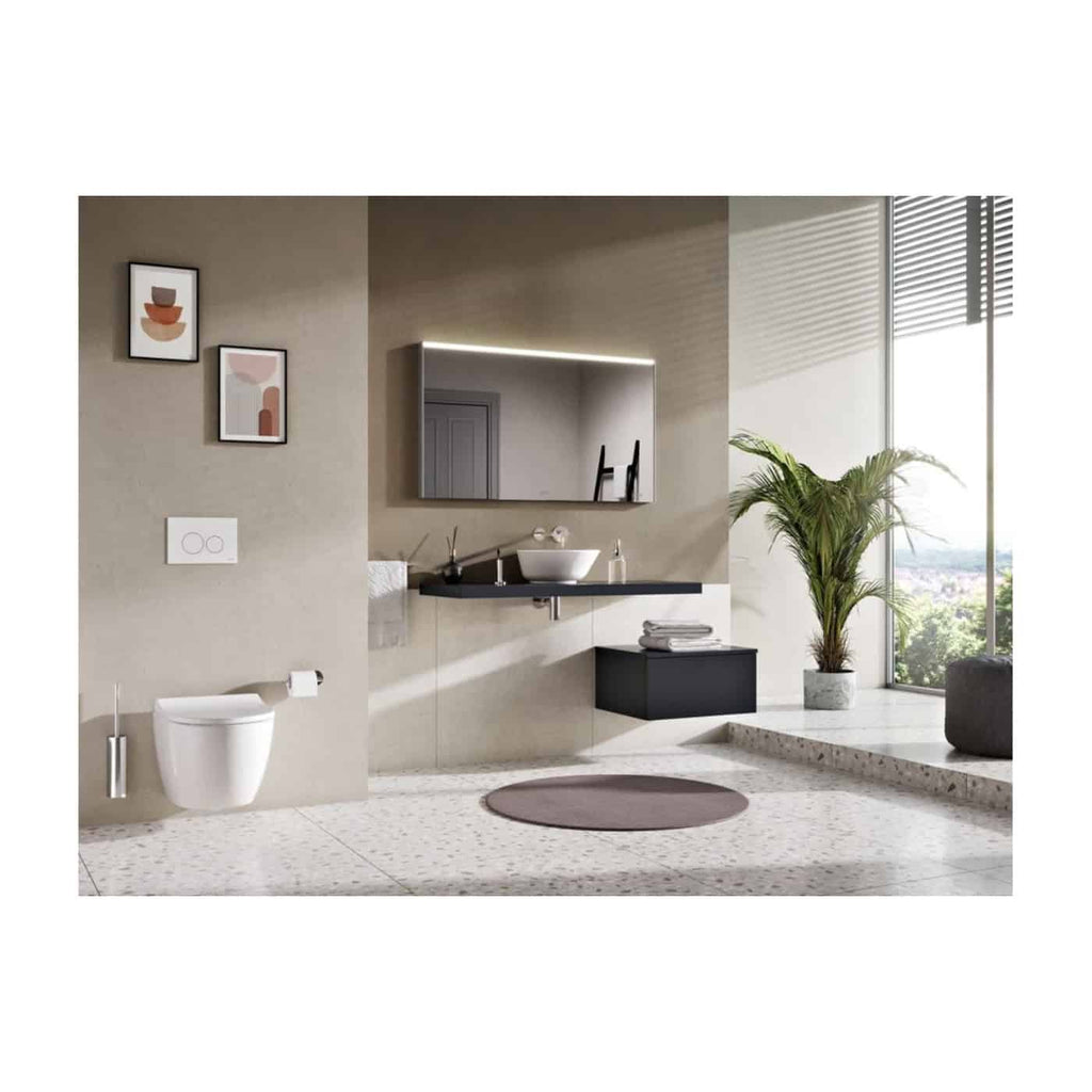 Sleek modern bathroom with wall-mounted toilet, minimalist basin, large mirror with integrated lighting, and stylish decor including framed artwork and a potted plant, featuring contemporary design and neutral tones.