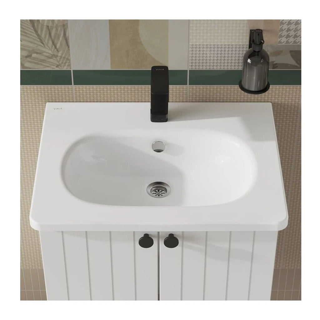 Sleek white bathroom sink with black tap and storage cabinet, modern design, ideal for contemporary bathrooms, complemented by wall tiles and a bottle of cleaning spray.