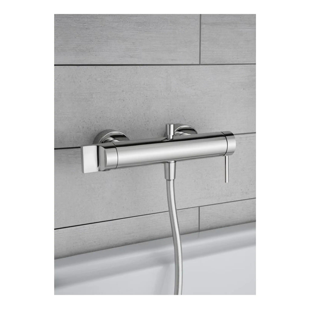 Sleek modern chrome bath filler tap with handheld shower in stainless steel finish against grey tiled wall, ideal for contemporary bathroom designs.