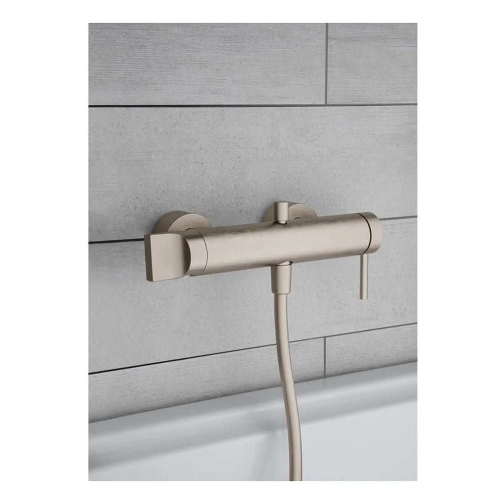 Sleek modern brushed nickel bath shower mixer tap with hand shower attachment on tiled bathroom wall.