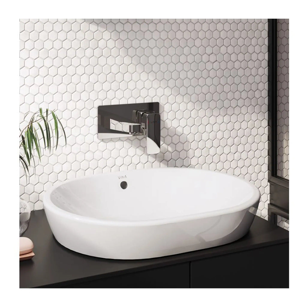 Modern white oval bathroom sink with sleek black wall-mounted faucet, set against a white hexagonal tile wall, creating a contemporary and elegant bathroom design.