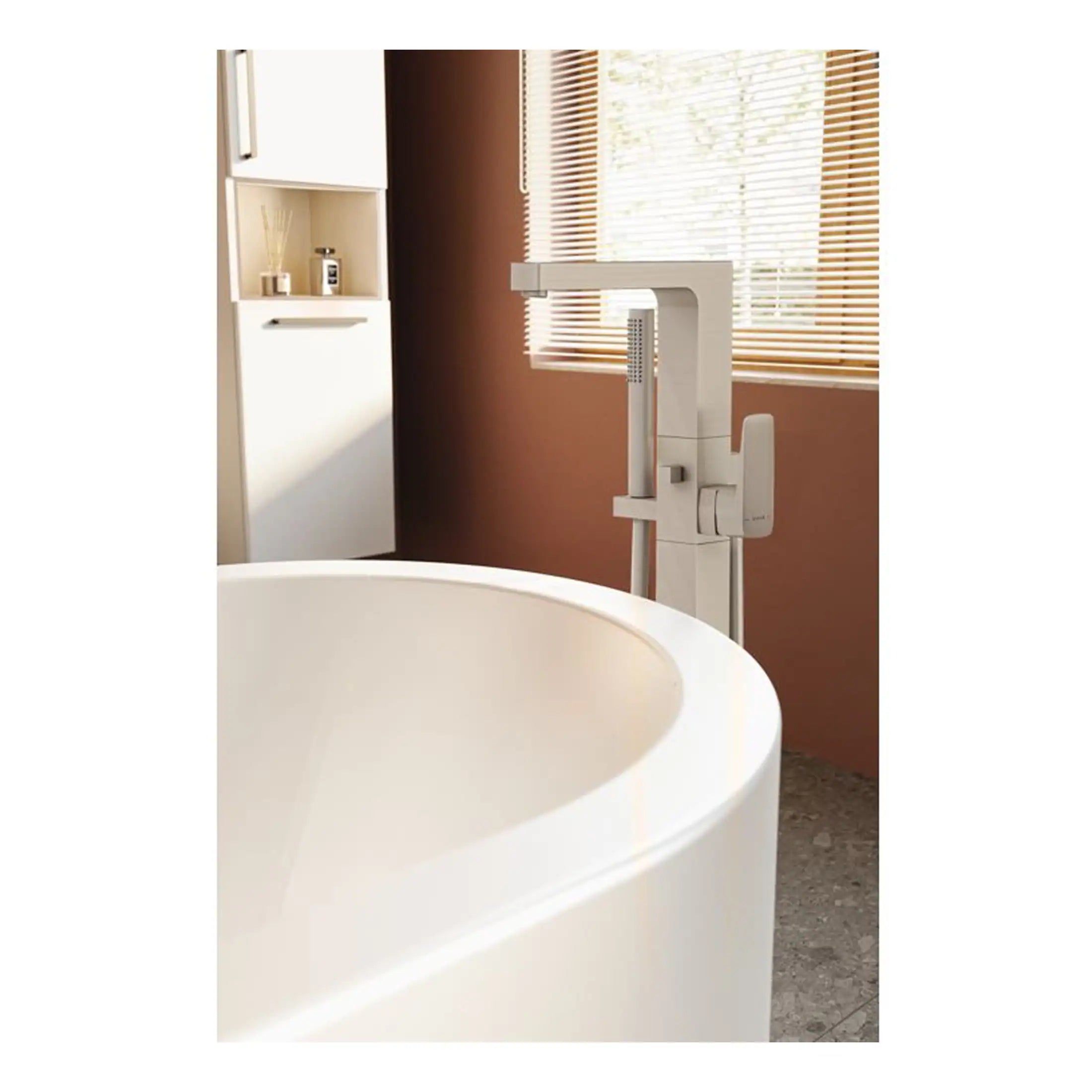 Sleek white bathtub with modern freestanding bath mixer tap in a contemporary bathroom with wooden window blinds and warm earthy tones. Perfect for stylish and functional bathroom design.