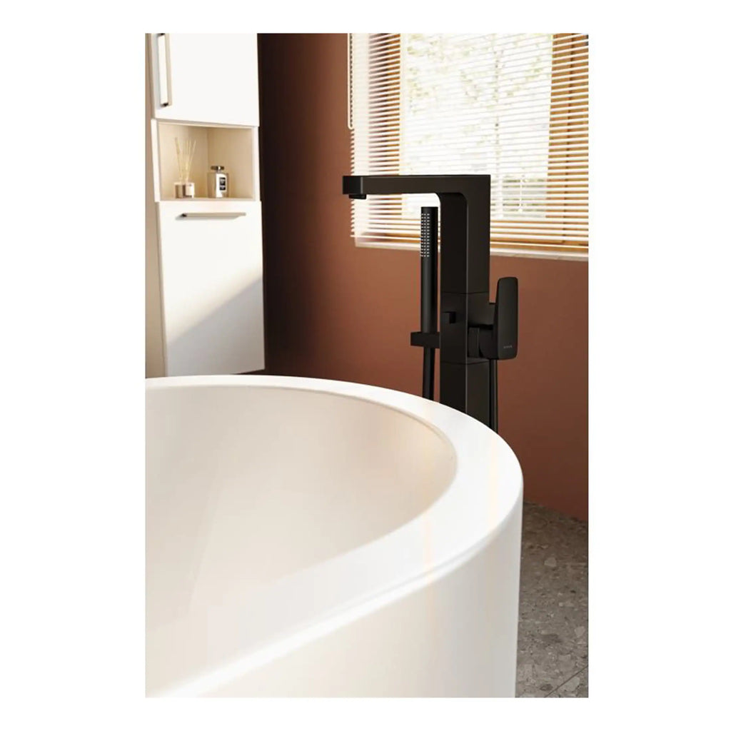 Sleek black freestanding bathtub mixer tap with modern design, installed near a luxurious bathtub in a contemporary bathroom with natural light and wooden blinds.