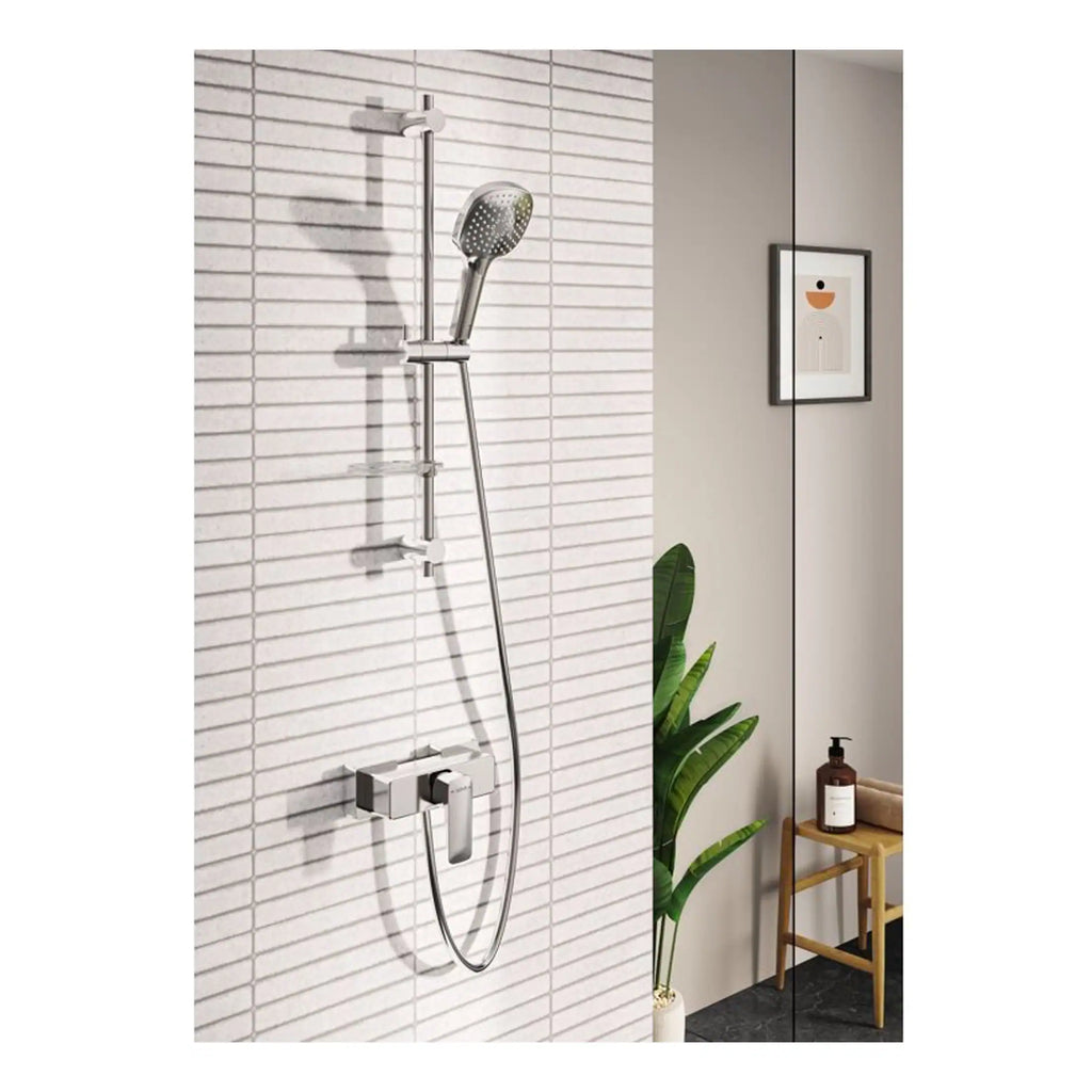 Modern chrome shower system with adjustable handheld showerhead on a tiled bathroom wall, complemented by minimalist decor including a potted plant and framed artwork.