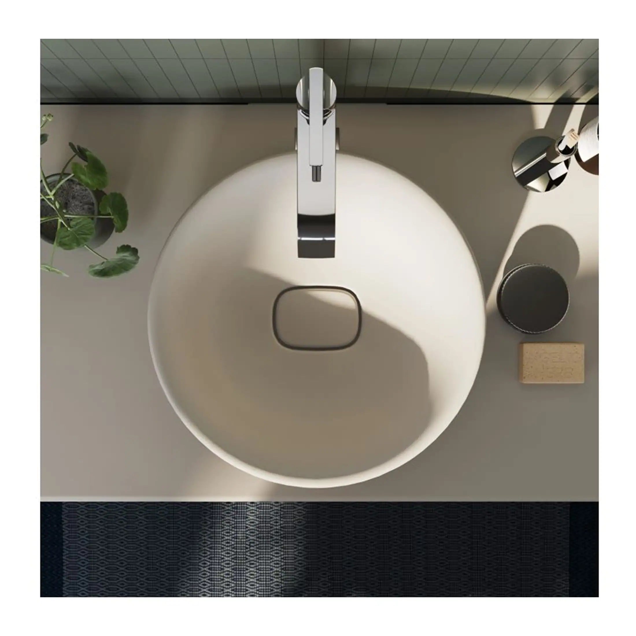Sleek white bathroom sink with modern chrome faucet, minimalist design, black soap dish, natural wooden brush, and green plant, showcasing contemporary bathroom fixtures and accessories.