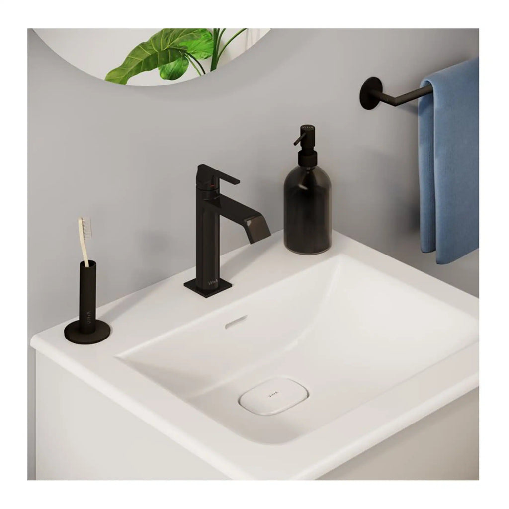 Elegant modern bathroom sink with black fixtures, soap dispenser, toothbrush holder, and a blue towel on black towel rail, creating a stylish minimalistic space for daily routines.