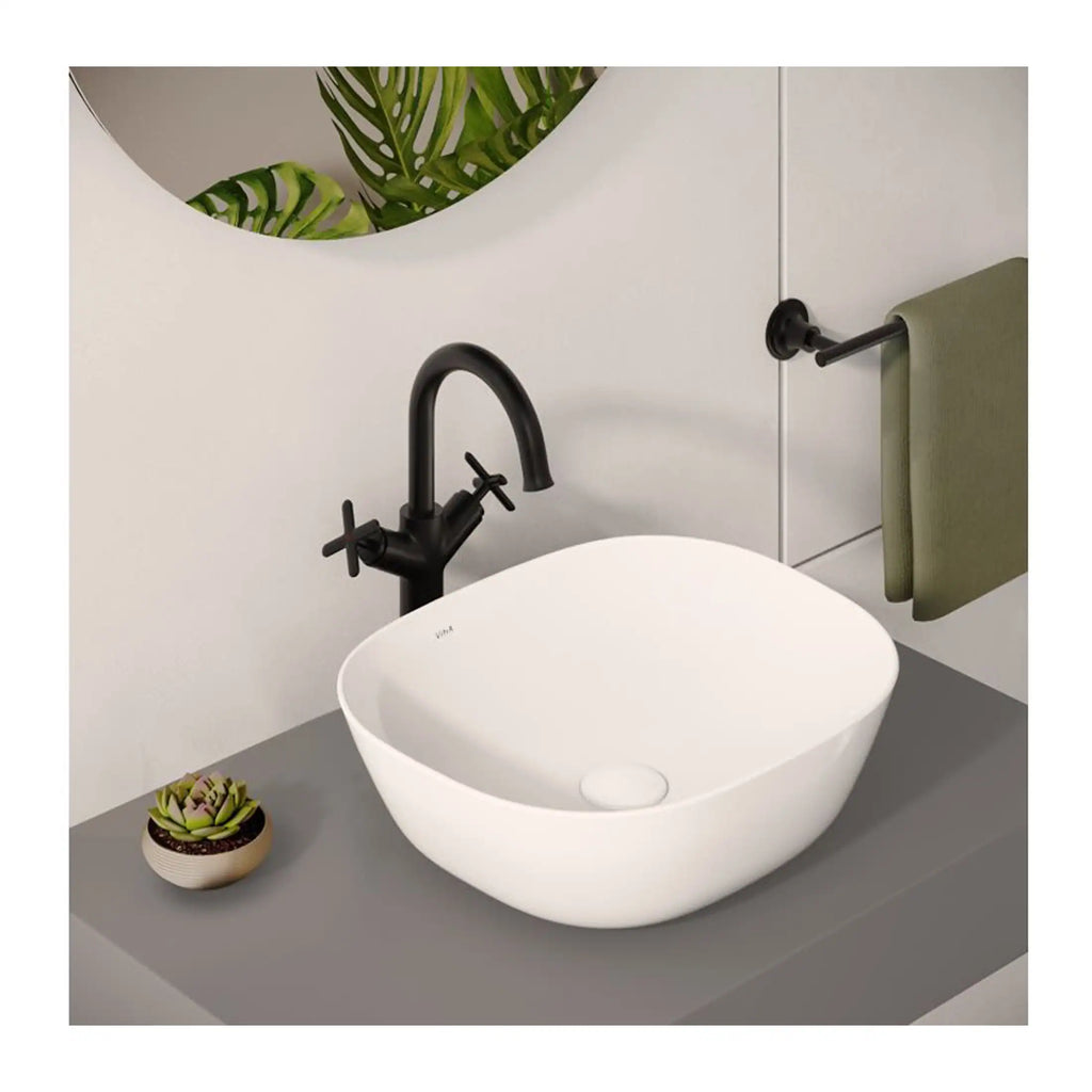 Sleek white bathroom basin with black matte faucet, modern minimalist design, grey countertop, decorative succulent plant, and olive green towel on black wall-mounted towel rail.